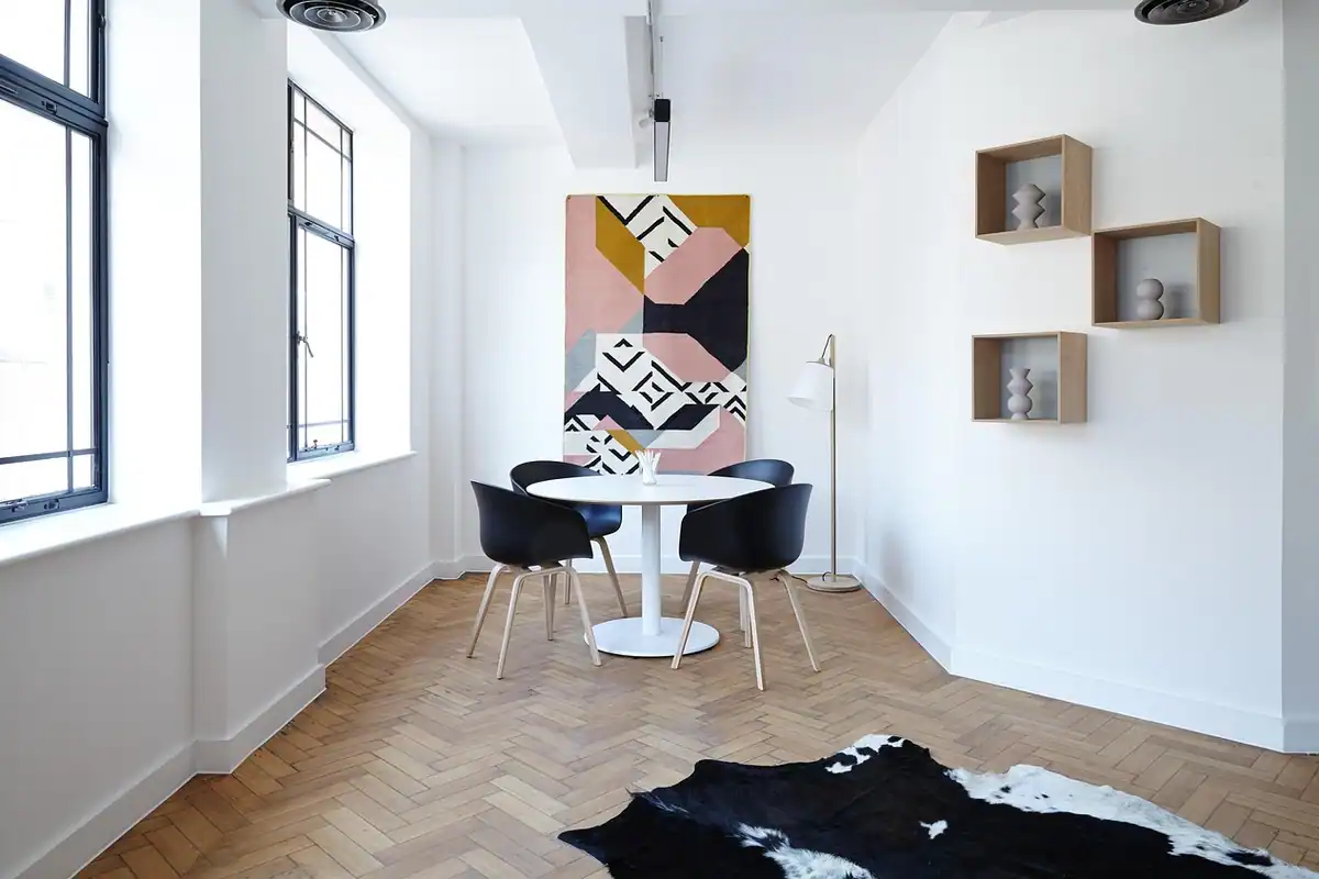 Living-room luminos cu masă rotundă și scaune negre, potrivit pentru un apartament de investiție