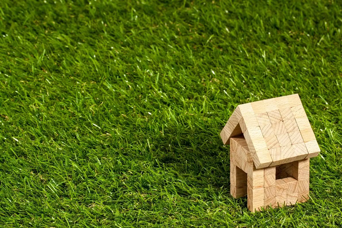 Căsuță mică din lemn pe iarbă verde, model pentru proprietăți comparabile