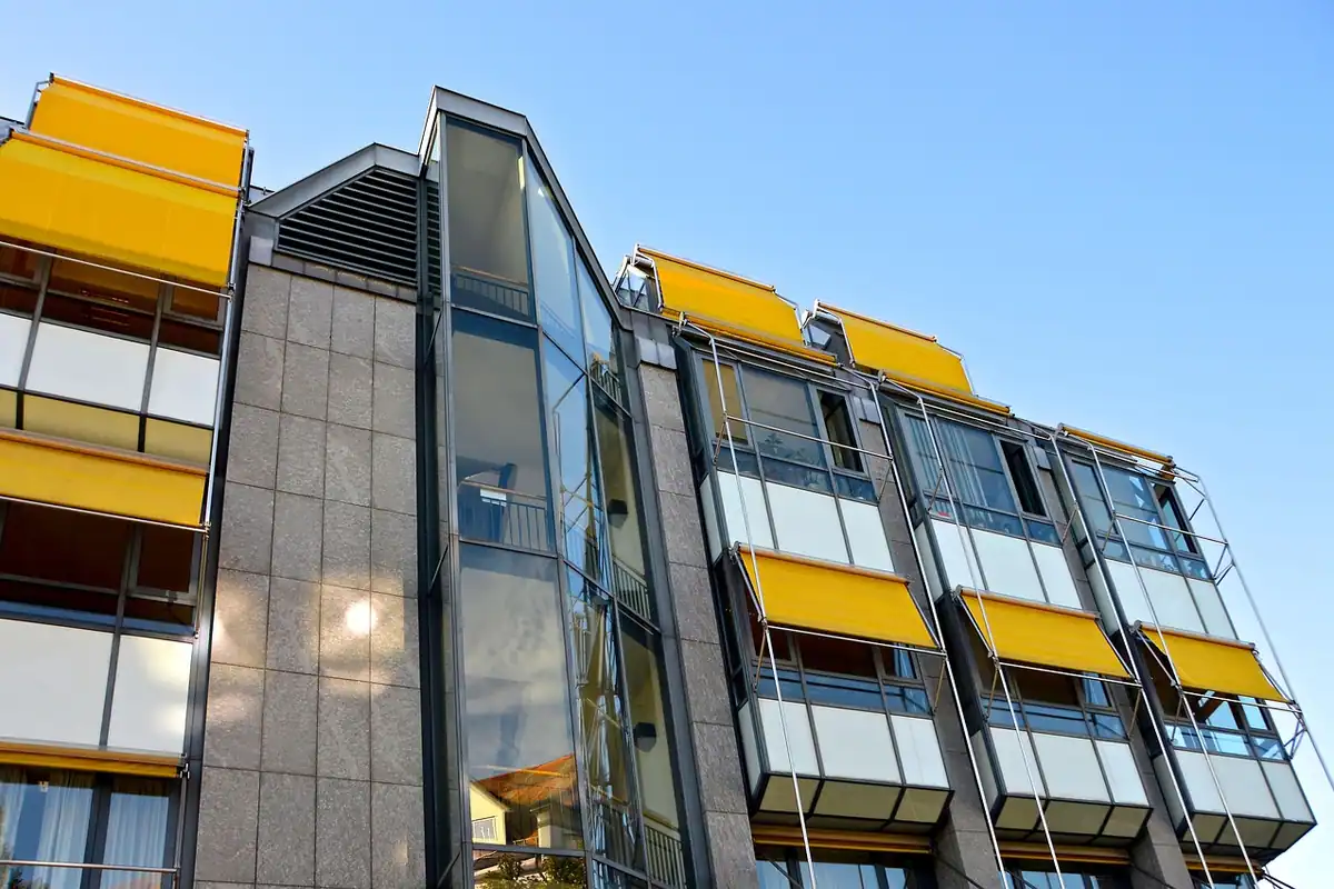 Casa scării dintr-un bloc, cu fațadă de sticlă și copertine de umbrire, văzută din lateral