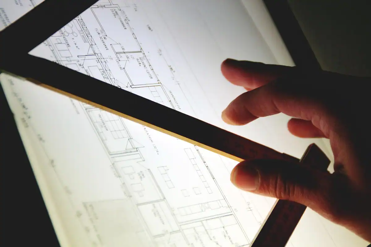 Mână care arată un plan de apartament pe o masă luminată
