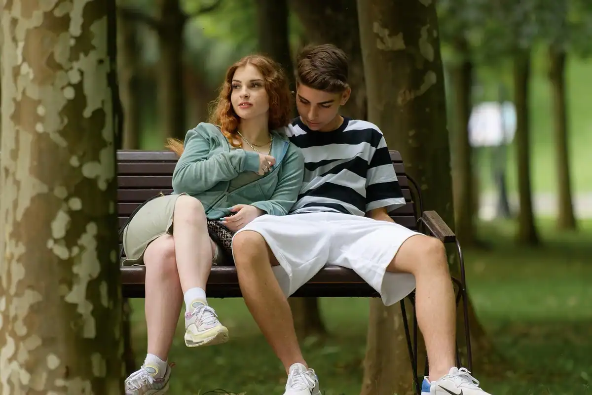 Cuplu tânăr stând împreună pe o bancă, într-un parc, în timp ce își planifică bugetul