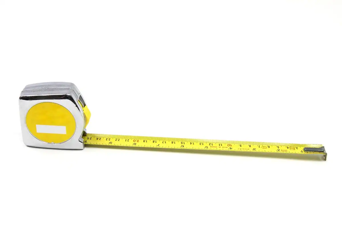 Ruletă galbenă și albă cu scală în centimetri și inci, folosită pentru măsurarea unui perete