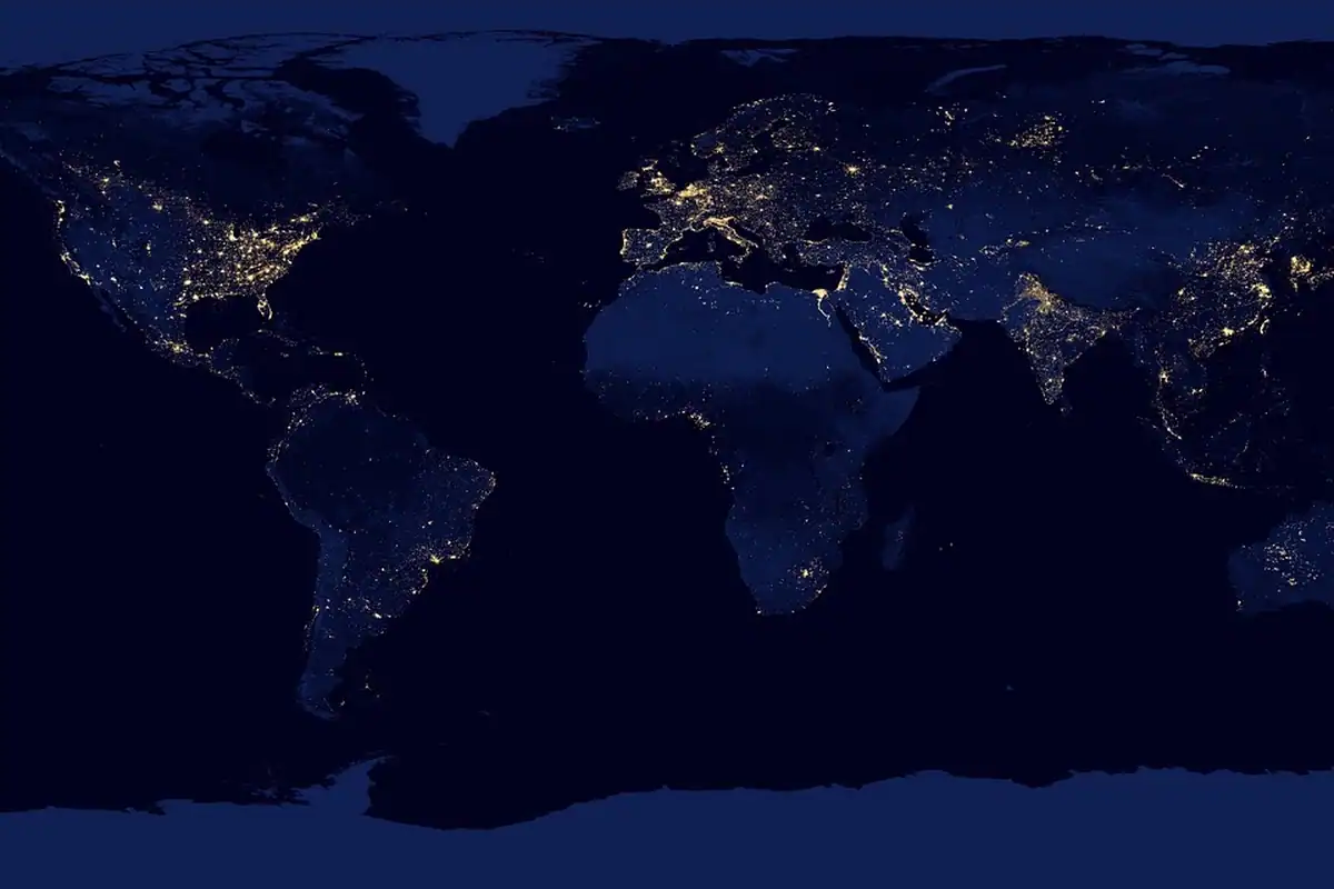 Hartă a lumii văzută din satelit, cu continentele luminate noaptea, pe fundal întunecat