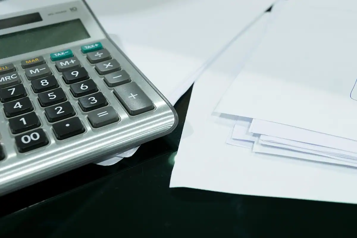 Calculator de birou lângă foi albe, pentru calculul investiției