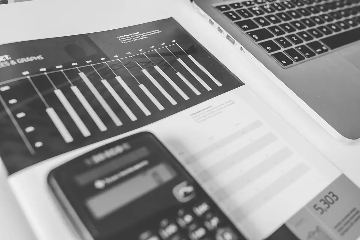 Calculator, laptop și grafice cu cifre financiare pe ecran, pentru calculul ratei de capitalizare