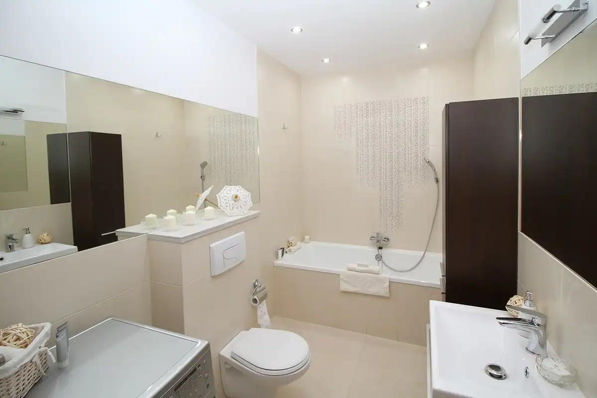 Baie renovată cu chiuvetă, oglindă și toaletă, cu faianță nouă și finisaje moderne