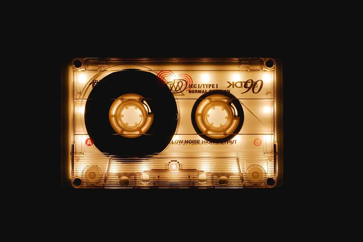 Casetă audio retro de culoare închisă, în prim-plan, lângă un radio vechi de epocă