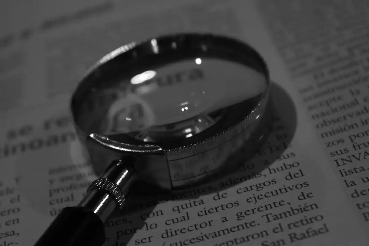 Lupă așezată peste un document din hârtie, mărind textul pentru a citi cu atenție actul